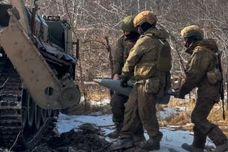 Russian soldiers carry ammunition for a Russian Pion self-propelled 203 mm cannon preparing to fire towards a Ukrainian position